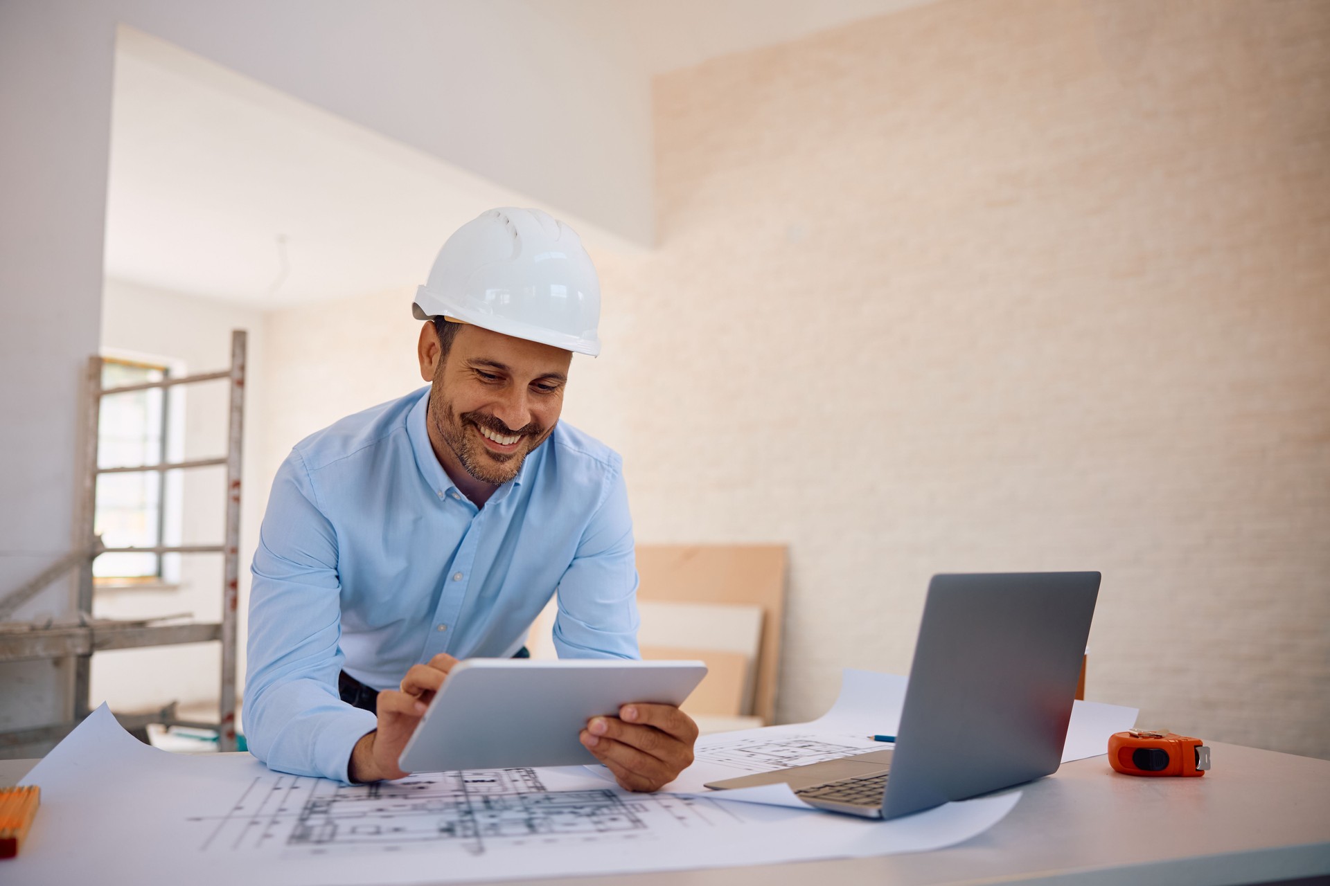 Happy civil engineer using digital tablet at construction site.
