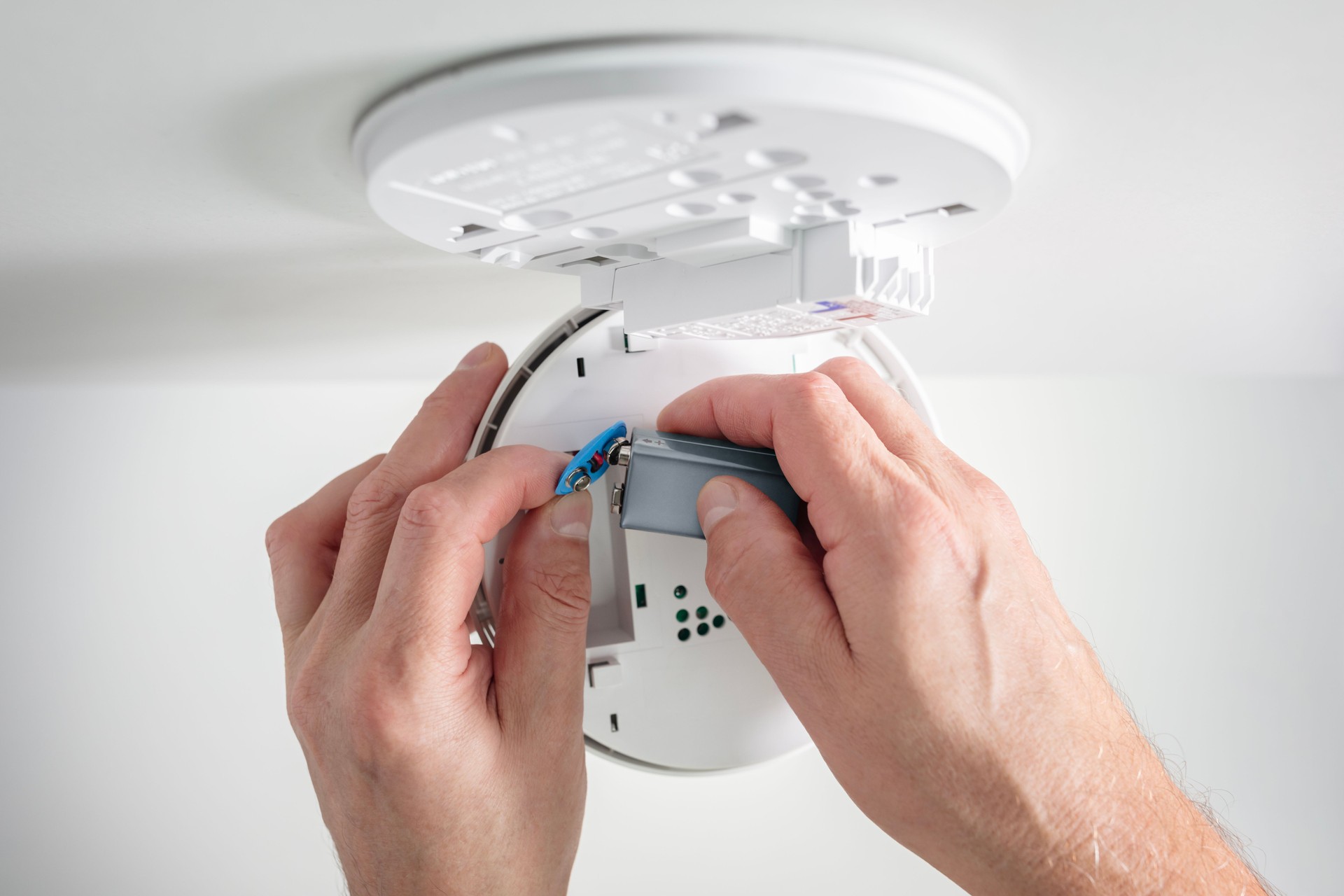 Inserting battery in home smoke detector and fire alarm installing, checking, testing or replacing battery